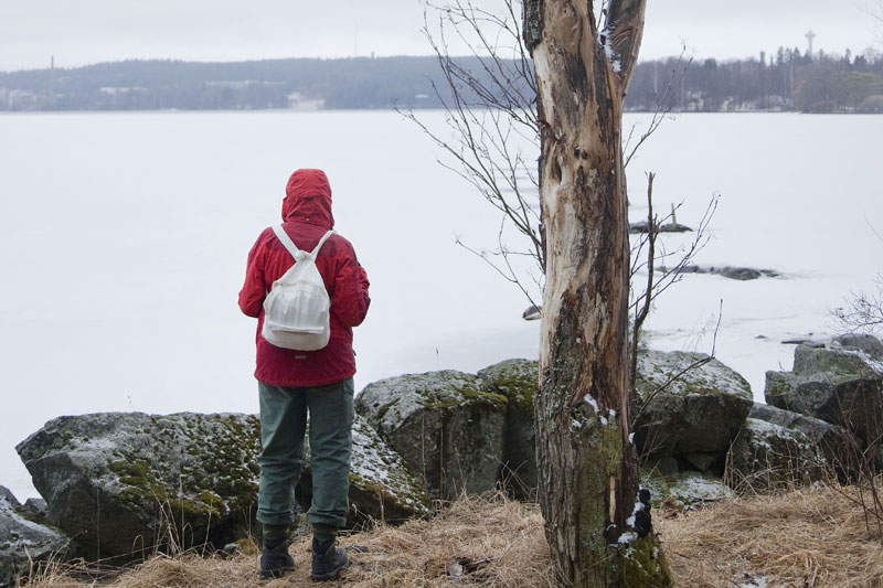 Nainen katselee kevättalvista järvimaisemaa.