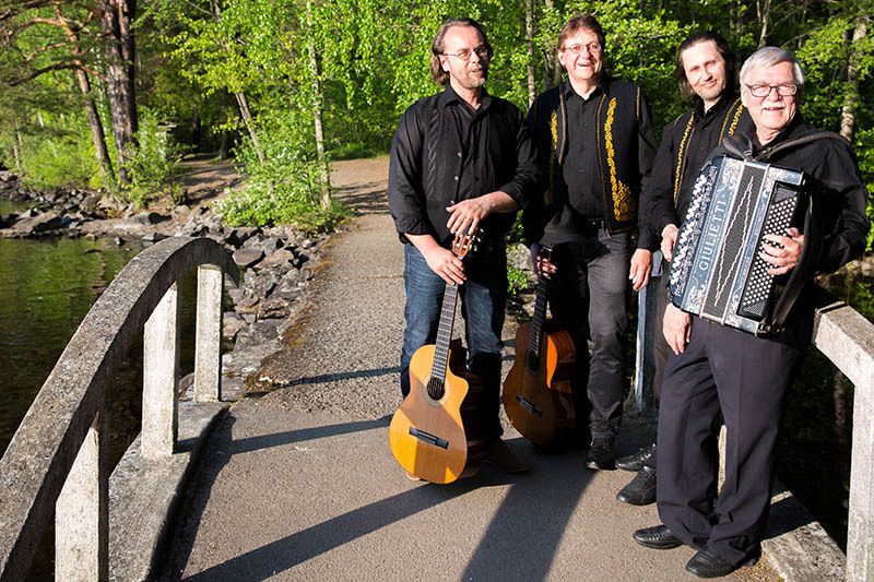 Neljä miestä seisoo sillalla, käsissä soittimet.