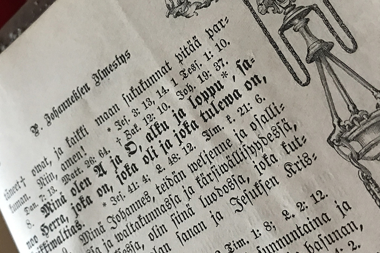 Vanhan Raamattu on avattu Johanneksen ilmestyksen kohdalta. Lause ”Minä olen A ja O” on korostettu.