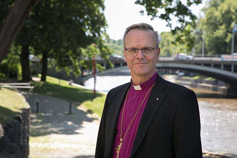 Arkkipiispa Tapio Luoma hymyilee kameralle ulkona kesäisellä ilmalla.