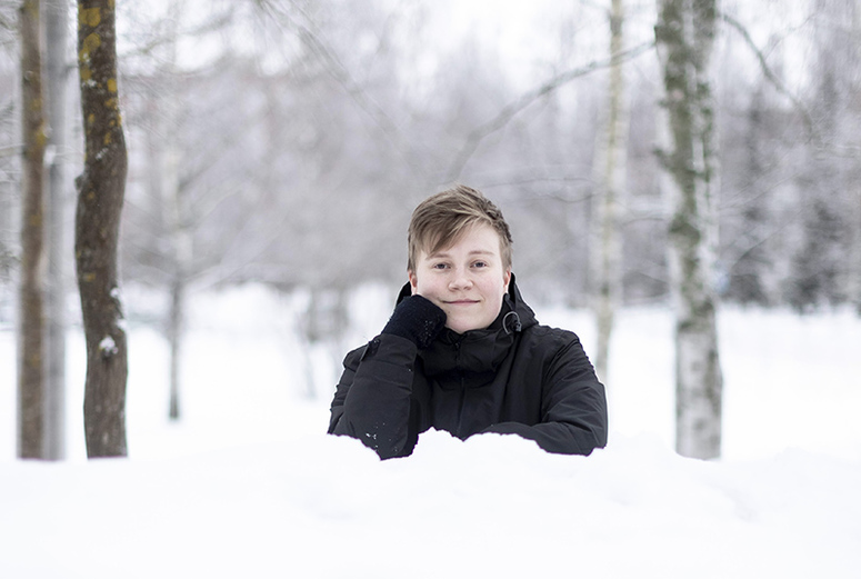 Nuorehko henkilö näkyy osittain lumikasan takaa.