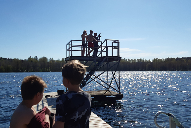 Uimahyppytorni ja laituri, etualalla kaksi pikkupoikaa selin.