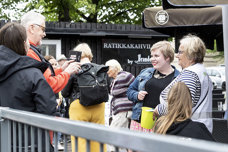 Mies ottaa matkapuhelimella kuvia väkijoukossa kahdesta naisesta.