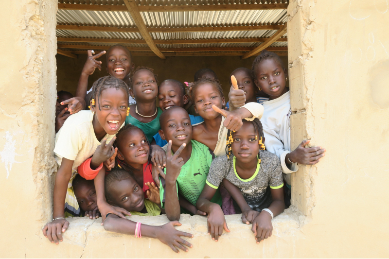 Senegalilaiset lapset kurkkivat koulun ikkunasta.