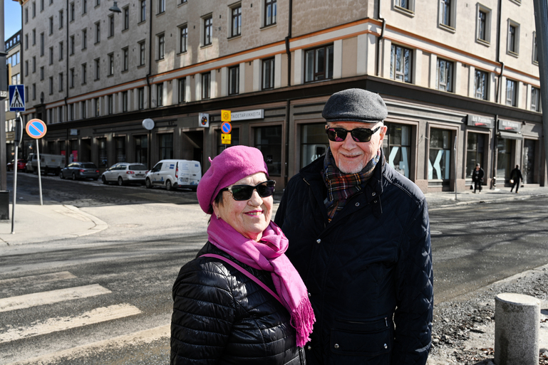 Vanhempi pariskunta katsoo kameraan ja hymyilee. Aurinko paistaa kirkkaasti ja heillä on silmillään aurinkolasit ja lämpimästi vaatetta.